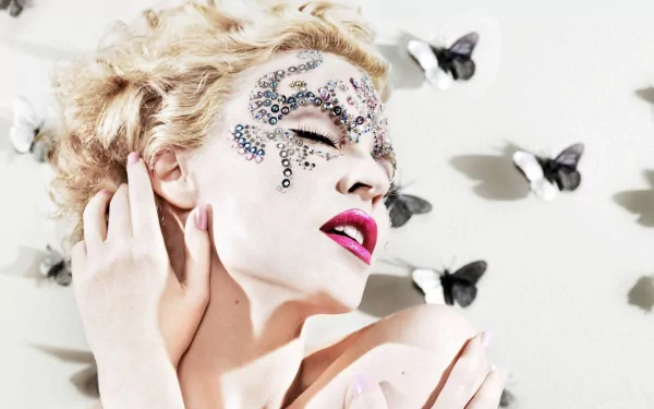 HD desktop wallpaper of singer Kylie Minogue with a cute expression, adorned with decorative gems on her face and surrounded by butterflies.