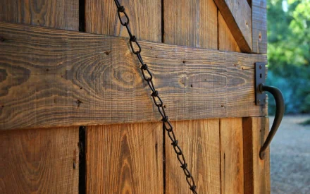A close-up view of a rustic wooden door, featuring detailed textures and a chain latch, creates a warm and inviting desktop wallpaper and background.
