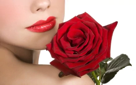 Close-up of a woman's lips adorned with bright red lipstick, gently holding a vibrant red rose. This HD PC desktop wallpaper blends beauty and nature seamlessly.