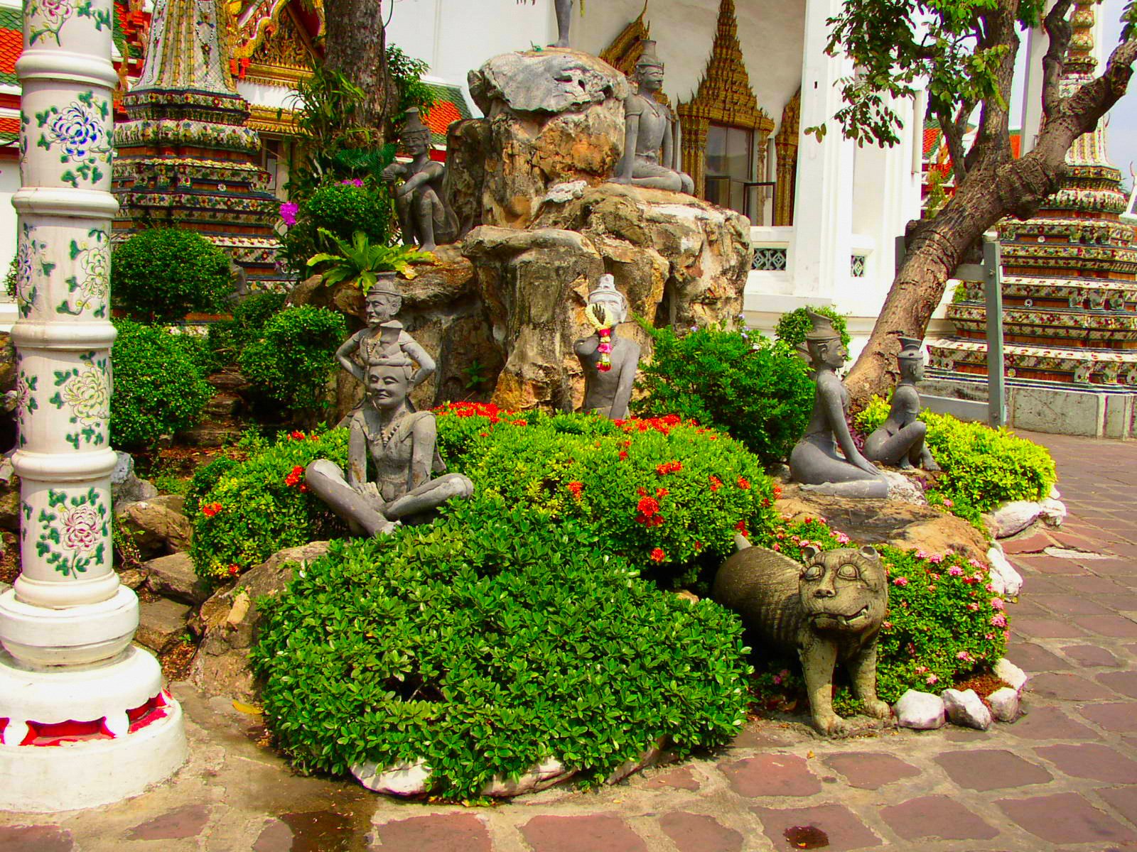 A serene garden featuring lush greenery, artistic stone sculptures, and vibrant flowers, creating a tranquil atmosphere for an invigorating HD PC desktop wallpaper.