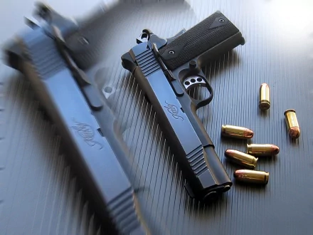 High-definition wallpaper featuring a Kimber pistol alongside several bullet casings, highlighting a sleek, modern design on a textured background.