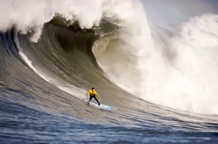 Surfer in a yellow shirt riding a massive wave, captured in stunning 4K Ultra HD, showcasing the thrill of surfing and sports action.