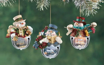 HD desktop wallpaper featuring three festive Christmas ornaments depicting snowmen on silver bells, set against a green holiday background.