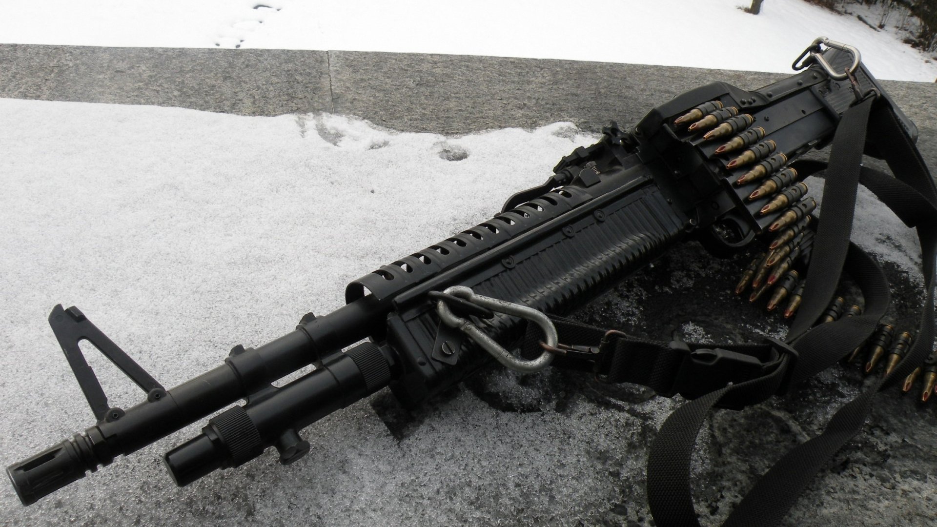 2K Quad HD PC desktop wallpaper: close-up of a man-made assault rifle with belt-fed ammunition resting on a snowy surface, high-contrast monochrome composition.