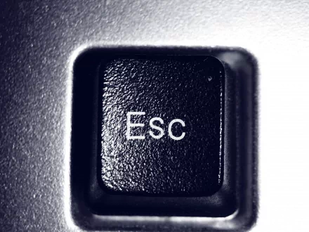 Close-up of an Escape key on a keyboard, featuring a textured black surface with white lettering, serves as a sleek HD desktop wallpaper highlighting technology and hardware.