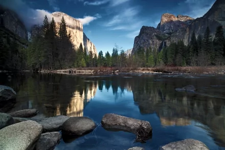 HD PC desktop wallpaper showcasing a serene river flowing through a forest with mountains in the background under a cloudy sky.