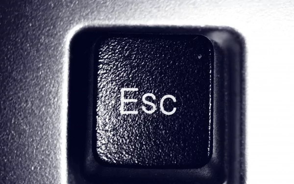 Close-up of an Escape key on a keyboard, featuring a textured black surface with white lettering, serves as a sleek HD desktop wallpaper highlighting technology and hardware.
