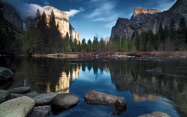 HD PC desktop wallpaper showcasing a serene river flowing through a forest with mountains in the background under a cloudy sky.
