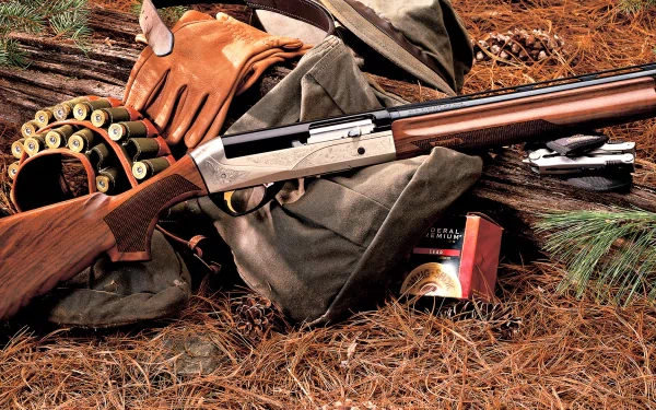 A shotgun rests on a bed of pine needles, surrounded by ammunition, gloves, and hunting gear, creating a detailed HD desktop wallpaper and background.
