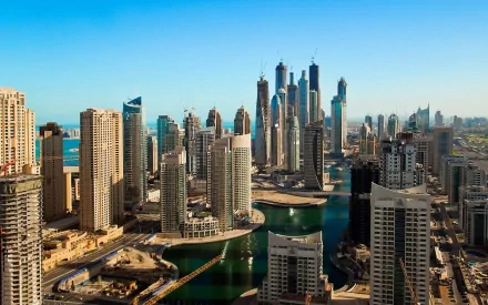 High-definition desktop wallpaper depicting the impressive skyline of Dubai with a mix of man-made skyscrapers and waterways under a clear blue sky.