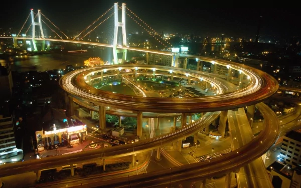 Nighttime view of Shanghai's Nanpu Bridge with its illuminated circular ramp and city lights in the background, featured as an HD desktop wallpaper.