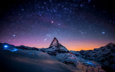 A breathtaking HD desktop wallpaper showcases the Matterhorn under a starry sky in Switzerland, with snow-covered mountains creating stunning natural scenery.