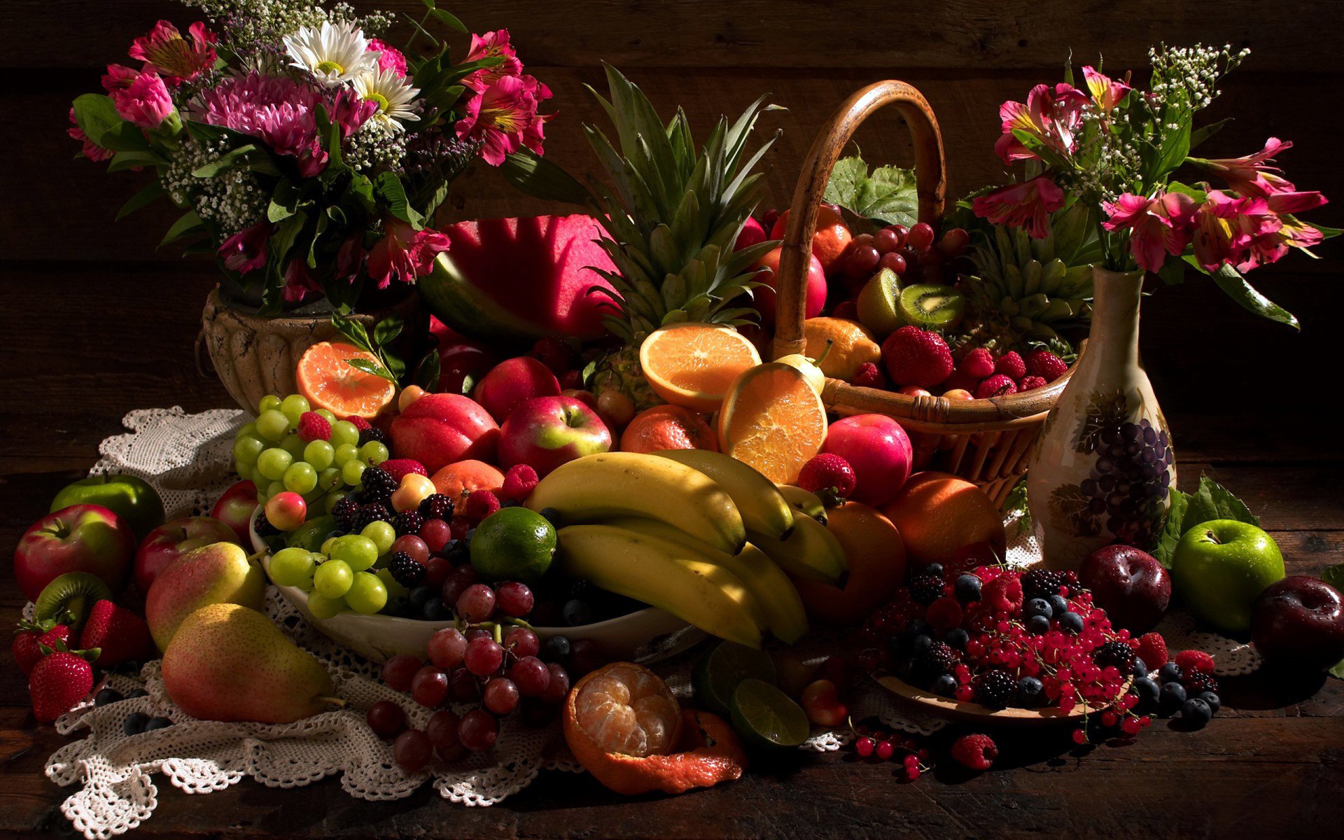 HD desktop wallpaper featuring a vibrant assortment of fresh fruits, including bananas, grapes, oranges, and berries, arranged beautifully alongside decorative flowers in baskets and vases.