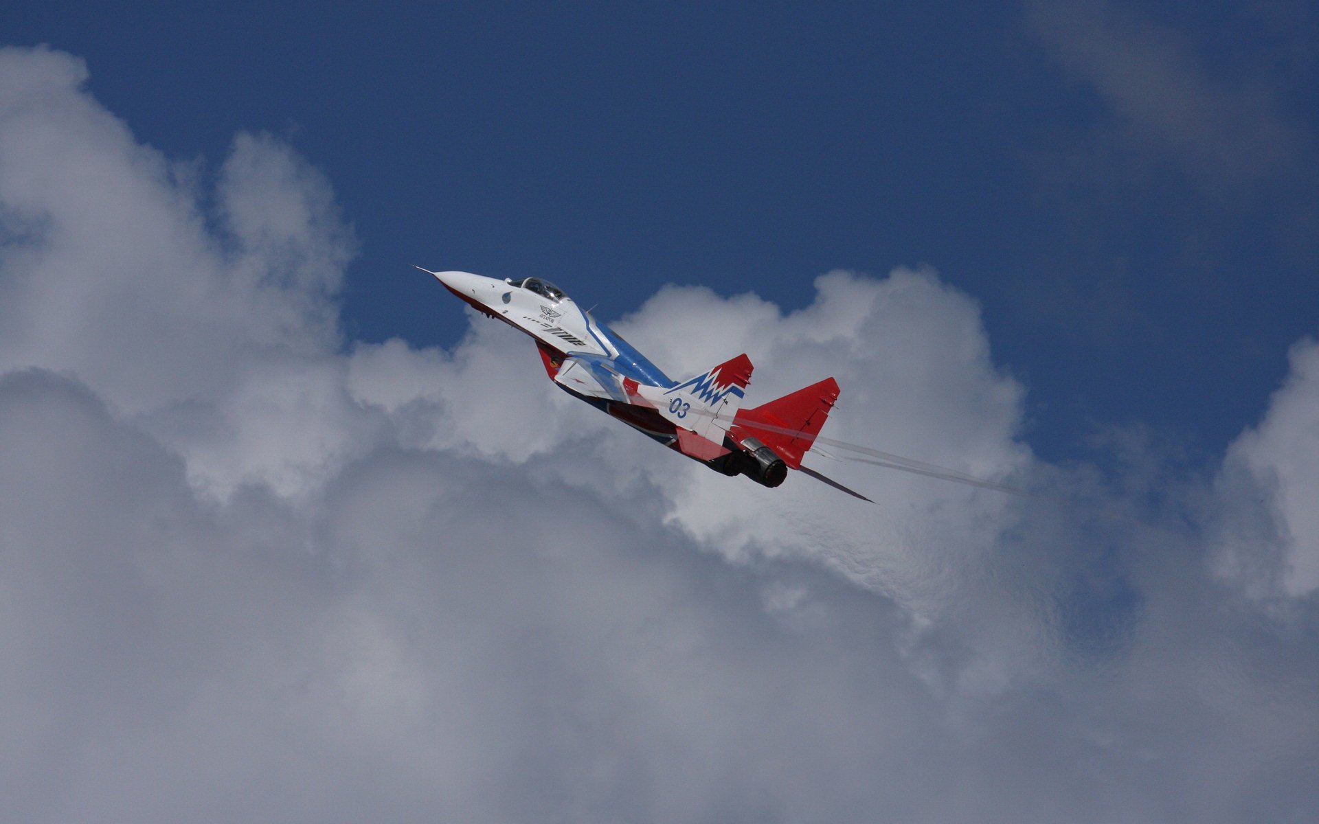 HD desktop wallpaper showcasing a military Mikoyan MiG-29 fighter jet soaring against a backdrop of blue sky and clouds.