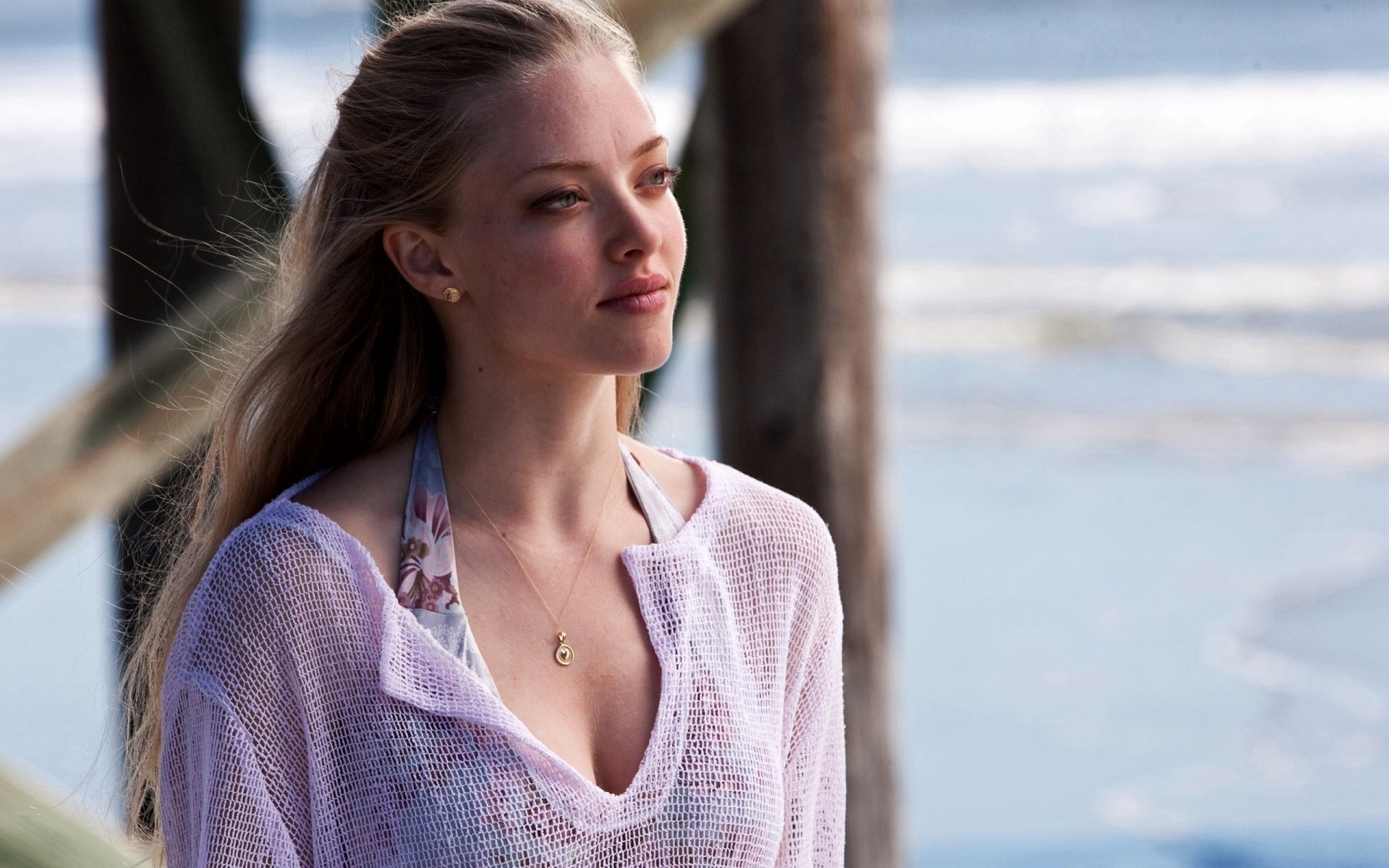 A serene HD desktop wallpaper featuring Amanda Seyfried by the ocean, showcasing her natural beauty and thoughtful expression against a tranquil beach backdrop.