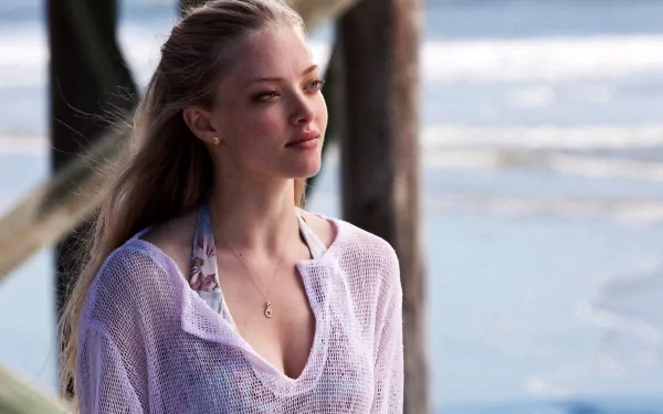 A serene HD desktop wallpaper featuring Amanda Seyfried by the ocean, showcasing her natural beauty and thoughtful expression against a tranquil beach backdrop.