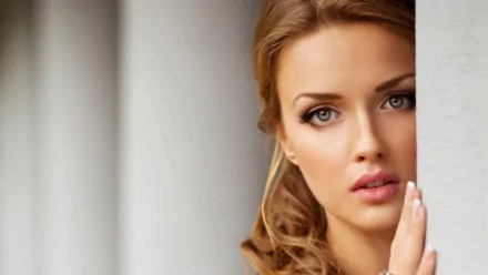 HD desktop wallpaper featuring the close-up of a woman's face, with soft lighting highlighting her features against a neutral backdrop.