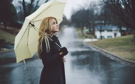 HD desktop wallpaper featuring Lenay Dunn standing in a rainy street, holding a yellow umbrella. The image evokes a serene and contemplative mood.