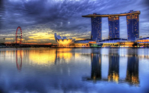A stunning HD wallpaper featuring Marina Bay Sands in Singapore, reflected in calm waters under a dramatic sky at sunset, showcasing the beauty of man-made architecture.