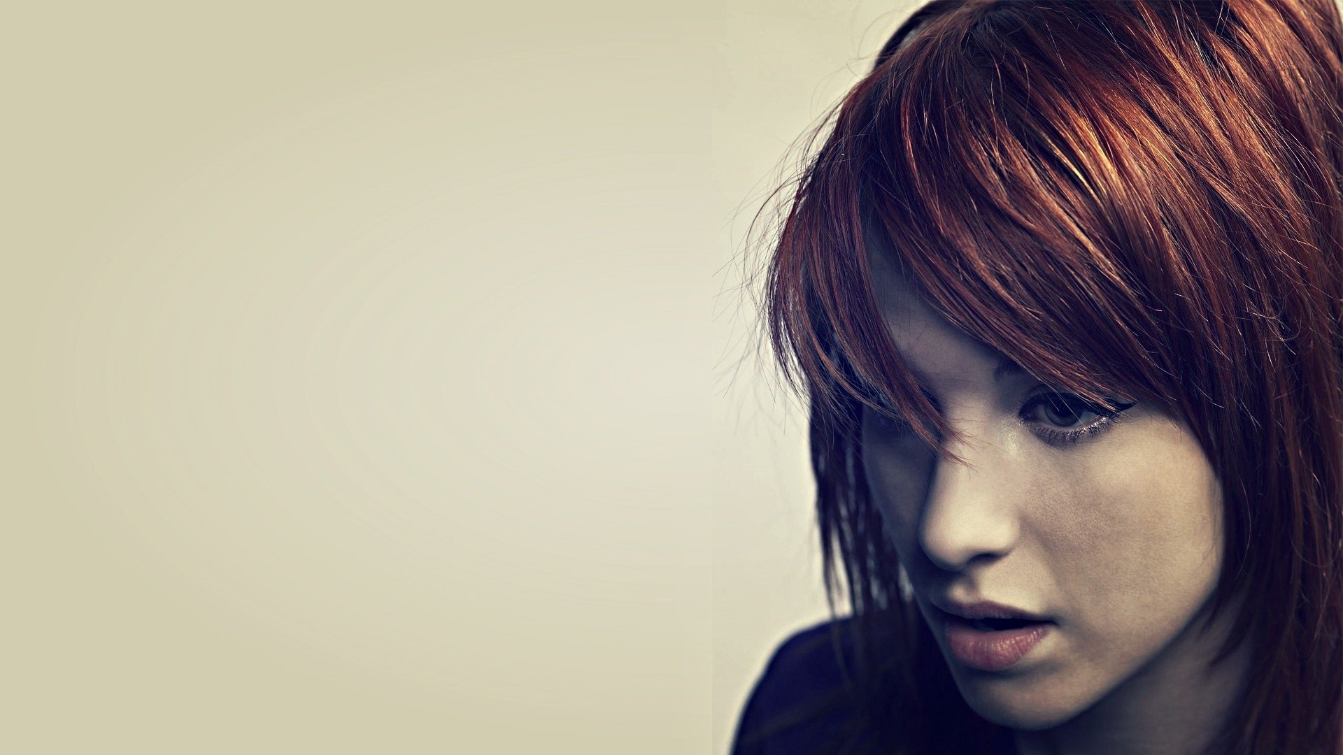 HD PC desktop wallpaper: red-haired female music artist in a moody three-quarter portrait against a pale, minimalist background.