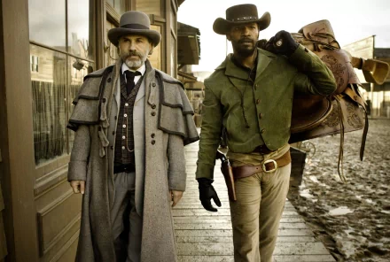 HD PC desktop wallpaper from the movie Django Unchained, featuring two key characters in period attire walking along a wooden sidewalk.