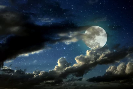 HD desktop wallpaper depicting a luminous, full moon peeking through clouds in a night sky filled with stars. Nature's beauty is captured in this stunning background.