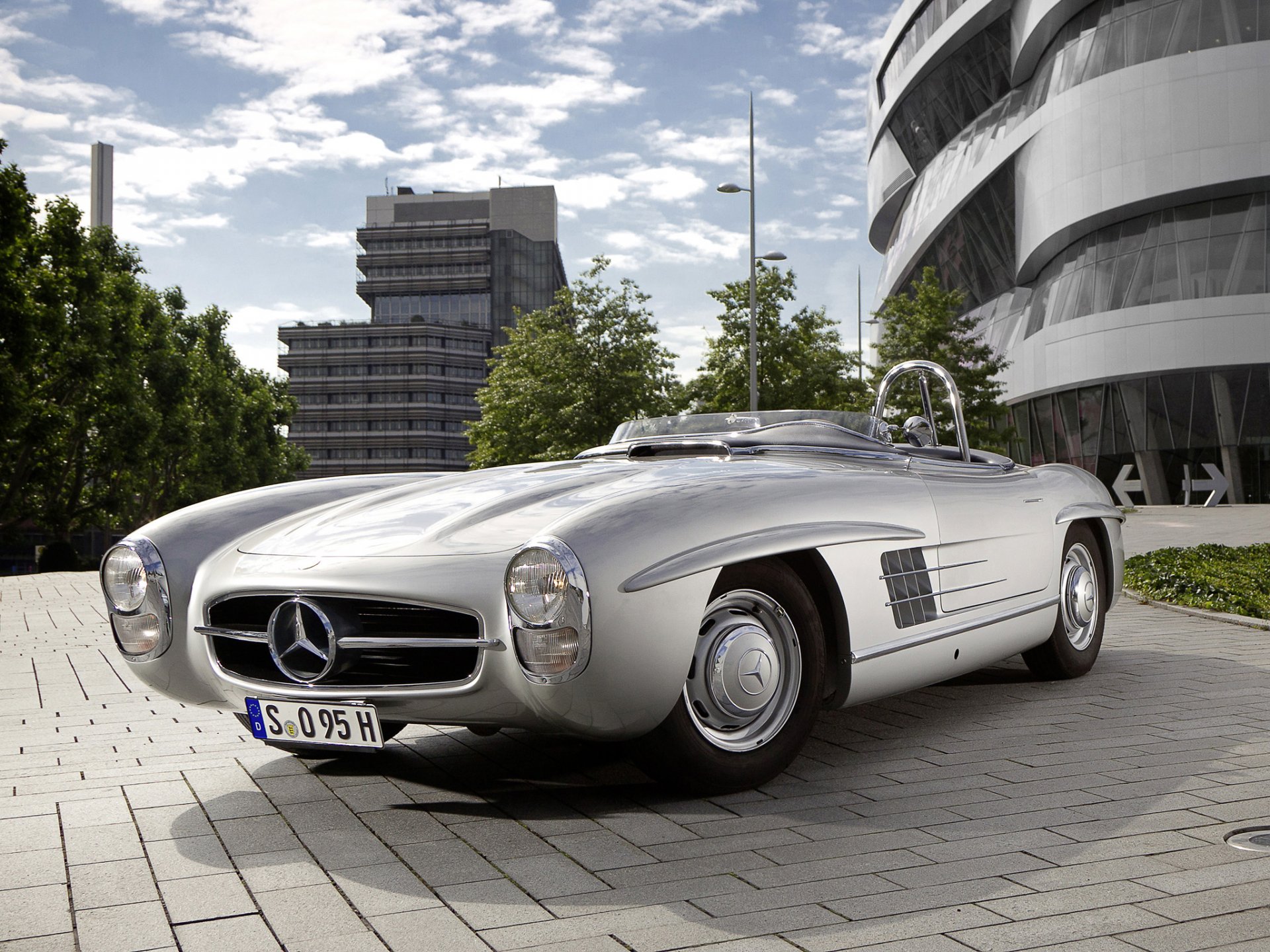 A sleek gray Mercedes-Benz 300SL convertible parked outdoors near modern buildings, featured as an HD PC desktop wallpaper.