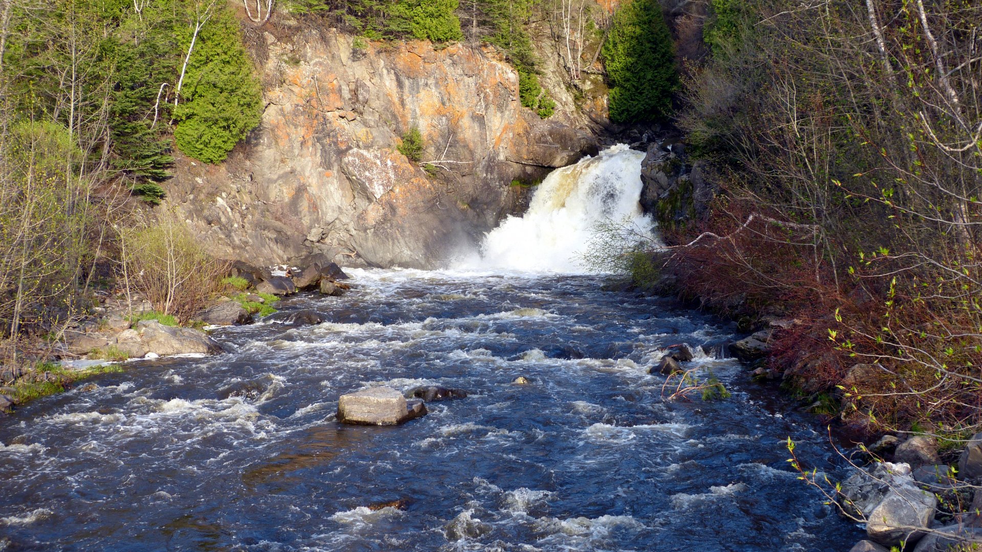 HDR photography captures a vibrant waterfall flowing through a rocky river surrounded by trees, presented in 4K Ultra HD for PC desktop wallpaper and background.