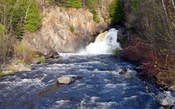 HDR photography captures a vibrant waterfall flowing through a rocky river surrounded by trees, presented in 4K Ultra HD for PC desktop wallpaper and background.