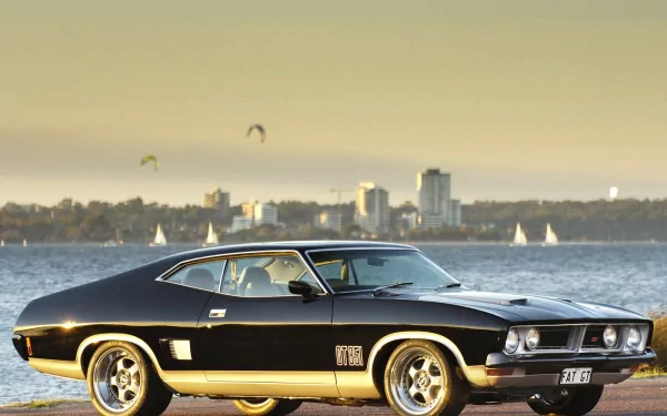 HD desktop wallpaper featuring a classic black Ford Falcon parked with a city skyline and water in the background.