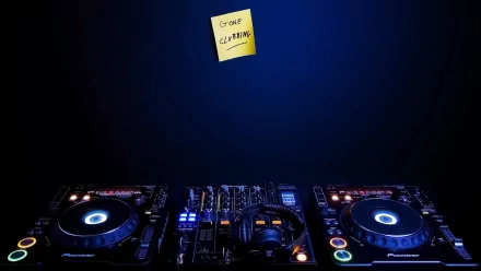 A vibrant HD desktop wallpaper featuring DJ equipment illuminated in blue light, with a sticky note reading Gone Cleaning adding a touch of humor to the music-themed scene.