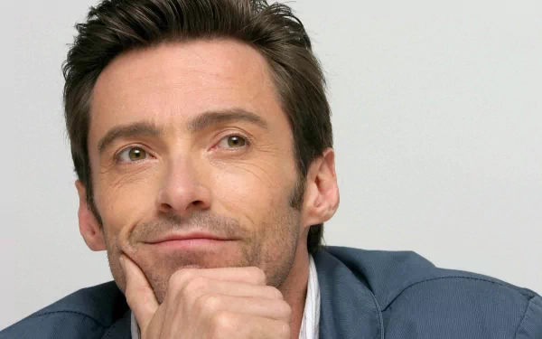 HD desktop wallpaper featuring celebrity Hugh Jackman thoughtfully resting his chin on his hand, with a light background.