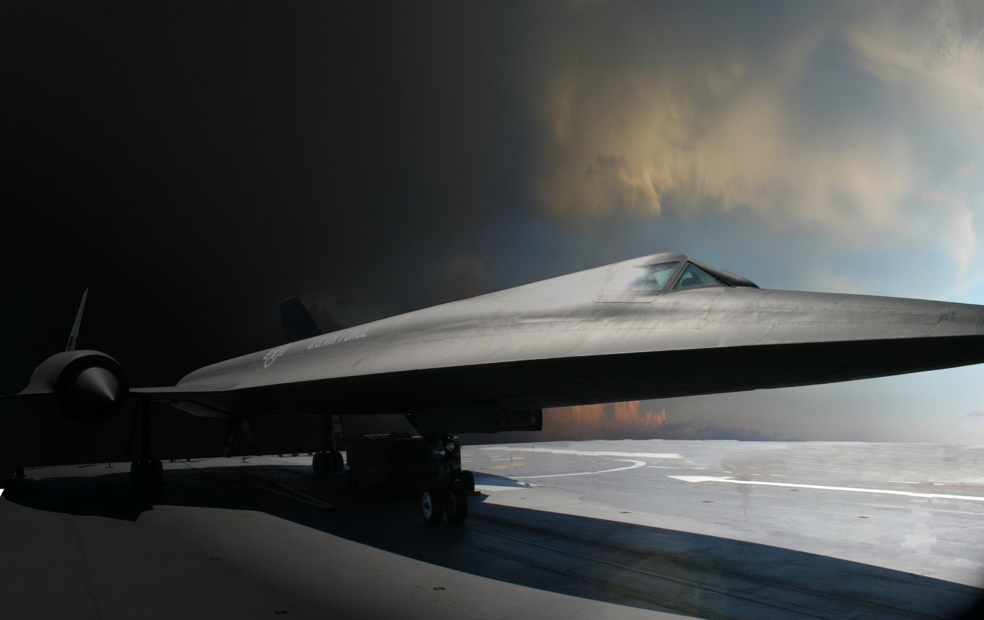 HD desktop wallpaper featuring a Lockheed SR-71 Blackbird military aircraft on a runway under dramatic sky lighting.
