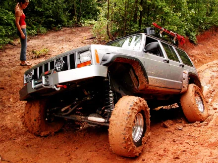 A rugged Jeep navigating a muddy trail, showcasing its off-road capabilities, surrounded by lush greenery—an exciting HD desktop wallpaper.