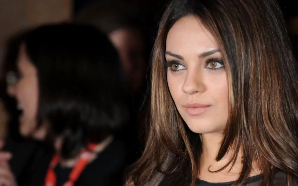 Mila Kunis is featured in this HD PC desktop wallpaper, showcasing her captivating look and striking gaze, set against a blurred background of an event.
