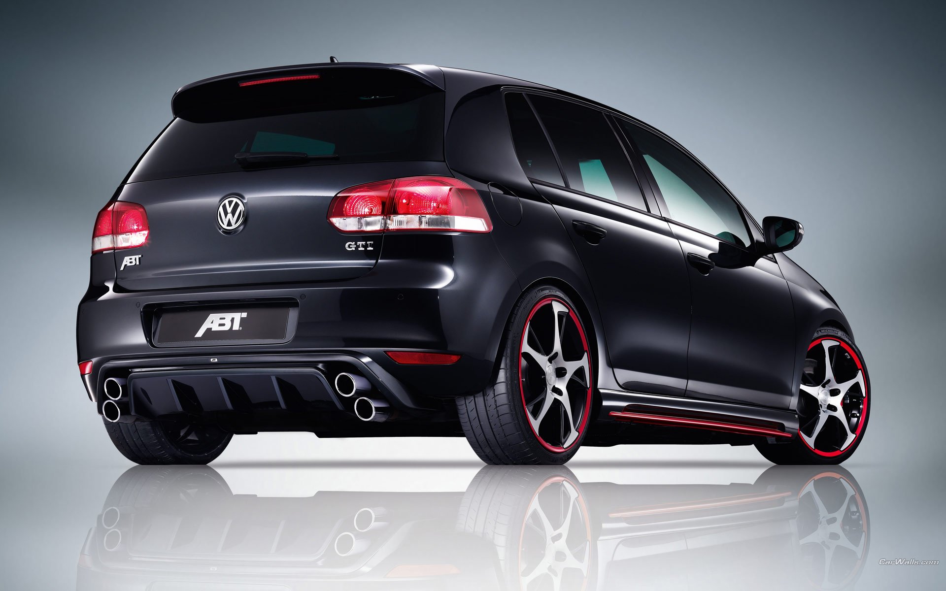 A sleek black Volkswagen GTI with distinctive red accents, showcased in a high-definition wallpaper, highlighting its sporty design against a smooth gradient background.