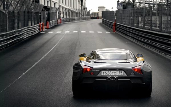 A sleek Marussia vehicle captured from the rear, racing down an empty track lined with barriers, showcasing its design and speed in a high-definition backdrop.