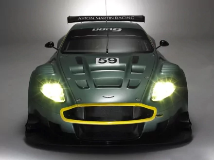 Front view of a green Aston Martin DBR9 race car with glowing headlights and number 59 on the hood, presented as an HD PC desktop wallpaper/background.