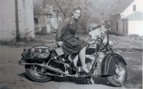 Black-and-white 4K Ultra HD desktop wallpaper of a vintage motorcycle with a woman seated outdoors in a residential area.