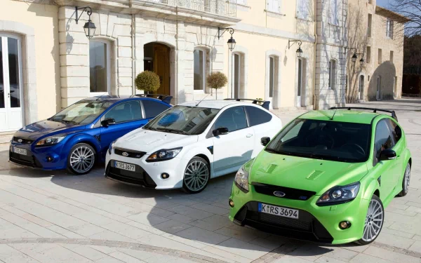 HD desktop wallpaper featuring three Ford Focus RS vehicles in blue, white, and green parked in front of a classic building.