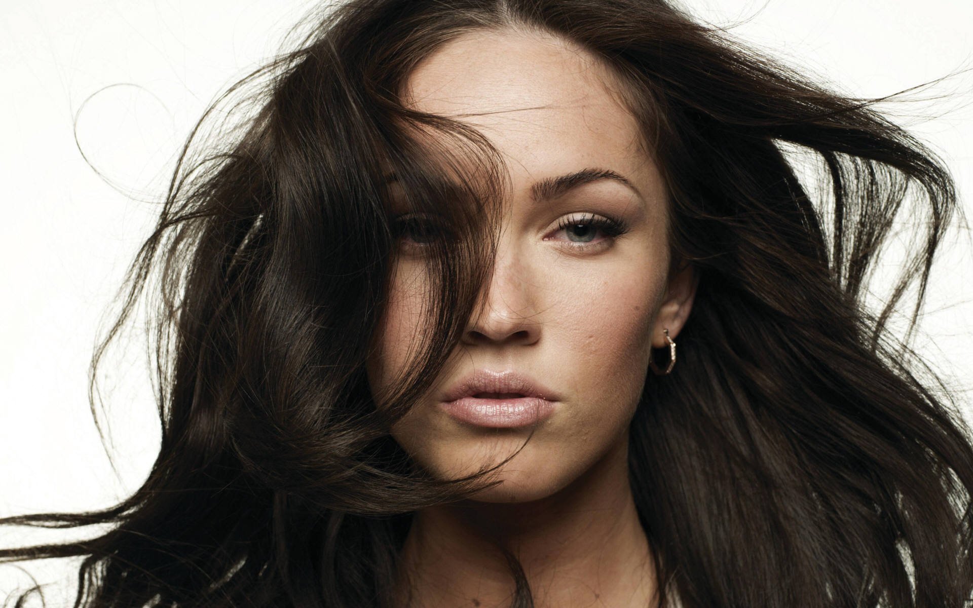 Stunning HD desktop wallpaper featuring celebrity Megan Fox with flowing hair and a captivating expression against a minimalistic background.