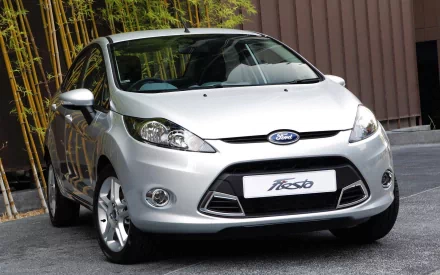 Silver Ford Fiesta hatchback parked by bamboo and a modern wall, shown as an HD PC desktop wallpaper background.