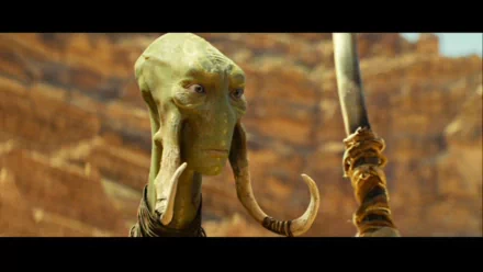 HD PC desktop wallpaper and background from the movie John Carter: close-up of a green, long-faced alien with tusk-like appendages holding a staff before a canyon.