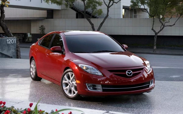 Red Mazda sedan vehicle parked on a modern city plaza, presented as an HD PC desktop wallpaper and background.