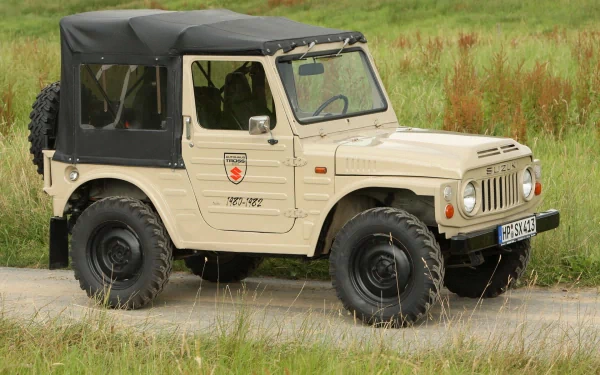 Beige Suzuki off-road vehicle with black soft top parked by grass; HD PC desktop wallpaper/background showcasing a rugged utility vehicle.