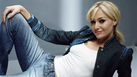 A stylish Australian actress, Portia de Rossi, poses confidently in a denim jacket and jeans, showcasing her blonde hair against a sleek background in this HD desktop wallpaper.