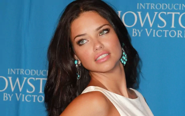 Adriana Lima poses elegantly against a blue backdrop, showcasing her beauty and style. This high-definition image serves as a stunning desktop wallpaper.