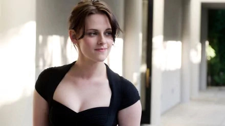 HD desktop wallpaper of American actress Kristen Stewart, looking to the side while standing in a well-lit hallway, wearing a black outfit.