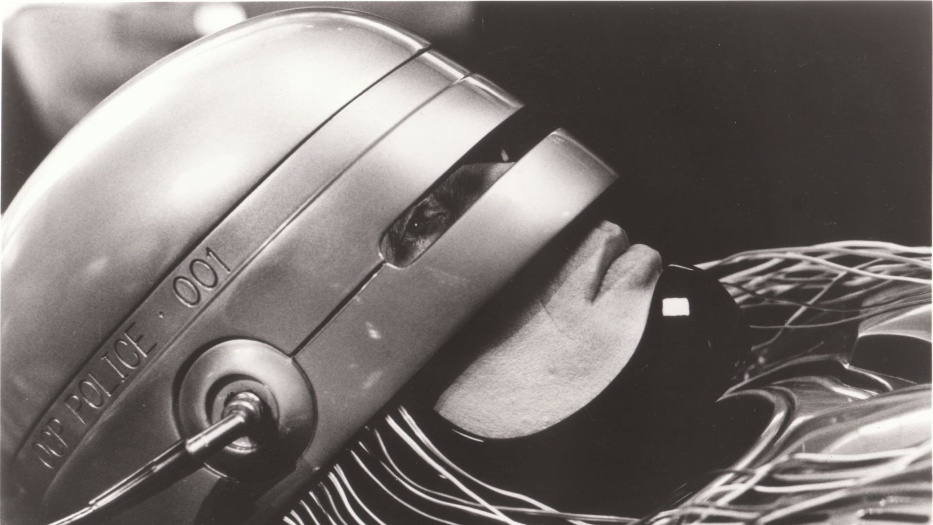 Monochrome HD PC desktop wallpaper of RoboCop (1987) — close-up of his helmet and faceplate from the movie, cinematic sci‑fi background.