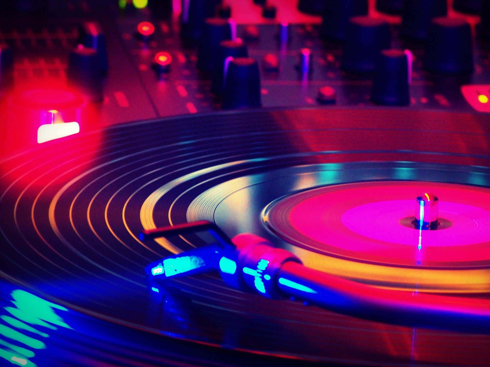 HD desktop wallpaper featuring an artistic close-up of a pastel-colored vinyl record spinning on a turntable, illuminated by vibrant neon lights.